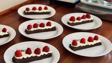A table with multiple plates of dessert, each topped with chocolate and raspberries.