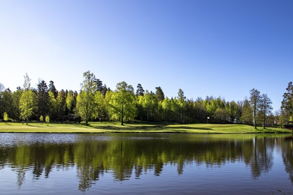 A serene lake with a reflection of trees and a clear sky. - Hotell Miskarp (Mjolby)
