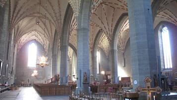 Un vaste intérieur de cathédrale, avec de hauts plafonds en voûte, des rangées de bancs en bois et un autel central.