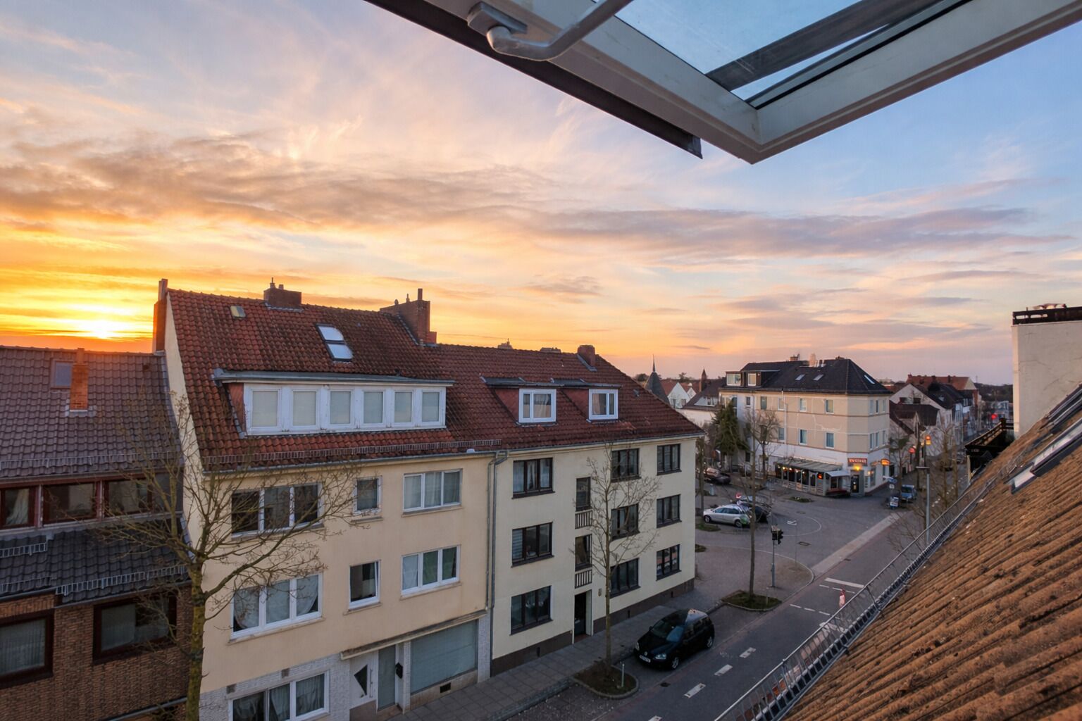 Ein Wohngebiet mit Gebäuden, einer Straße und einem Sonnenuntergang.