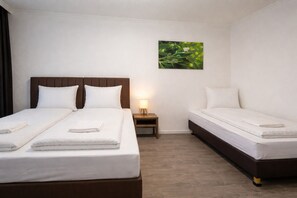 Een hotelkamer met twee bedden, een nachtkastje, een lamp en een aan de muur hangend schilderij.
