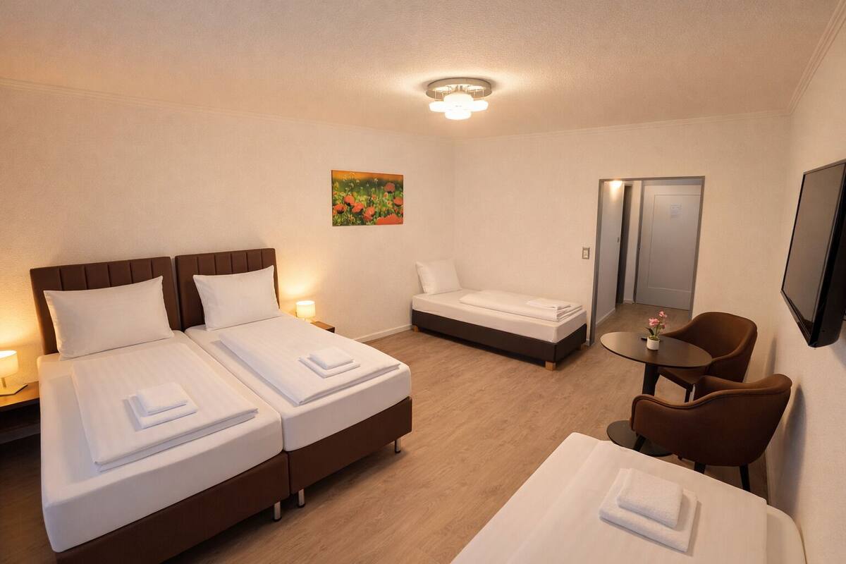 A hotel room with two beds, a desk, a chair, a mirror, and a painting on the wall.