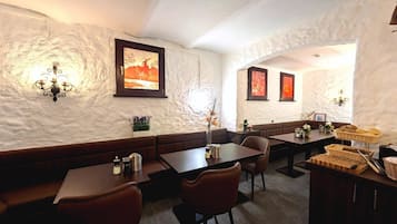 A restaurant with booths and tables, white textured walls, and framed artwork.