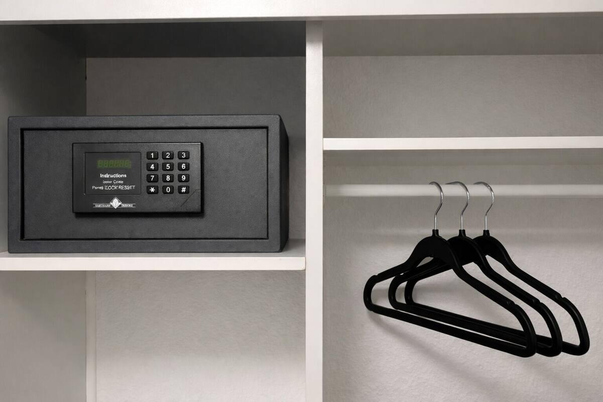 A black electronic device with a keypad and a digital display, and black hangers on a white shelf.