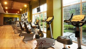 A gym with multiple stationary bikes and cardio machines, large windows, and a wooden floor. - Solo Paragon Hotel & Residences (Surakarta)