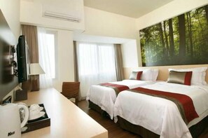 A hotel room with two beds, a desk, a TV, and a large forest-themed wall mural. - Solo Paragon Hotel & Residences (Surakarta)