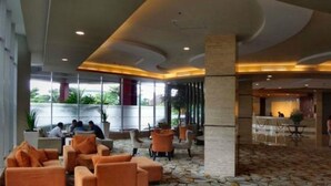A hotel lobby with orange seating, a patterned floor, and a reception area. - Solo Paragon Hotel & Residences (Surakarta)