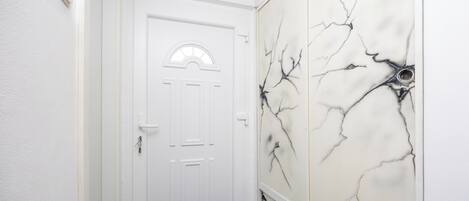 A hallway with a white door and a wall with a marble-like design.
