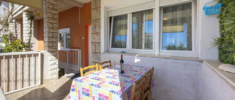 An outdoor patio with a table set for two, a stone pillar, and a window with a view.