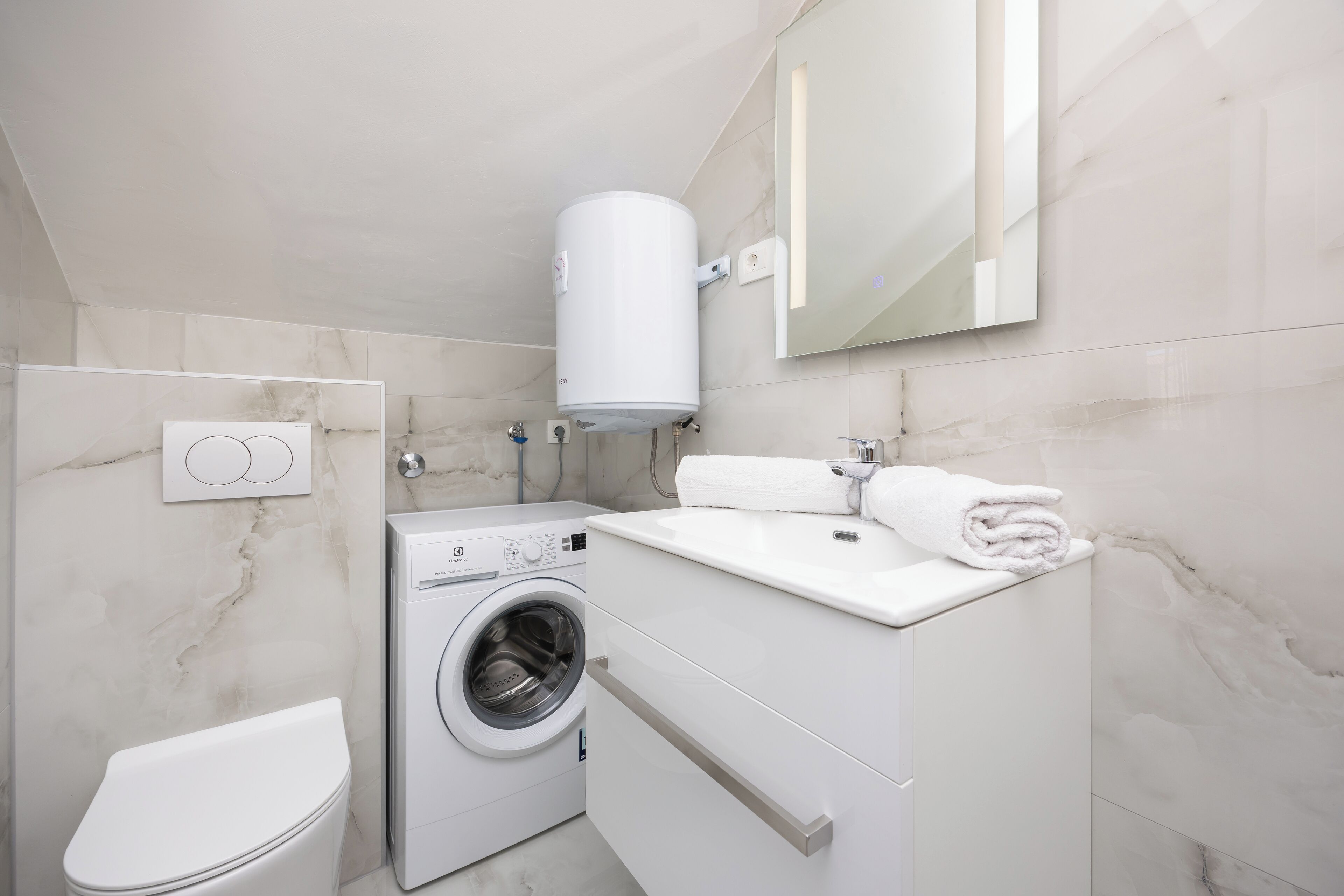 Ein modernes Badezimmer mit Waschmaschine, Toilette, Waschbecken und Handtuchhalter.