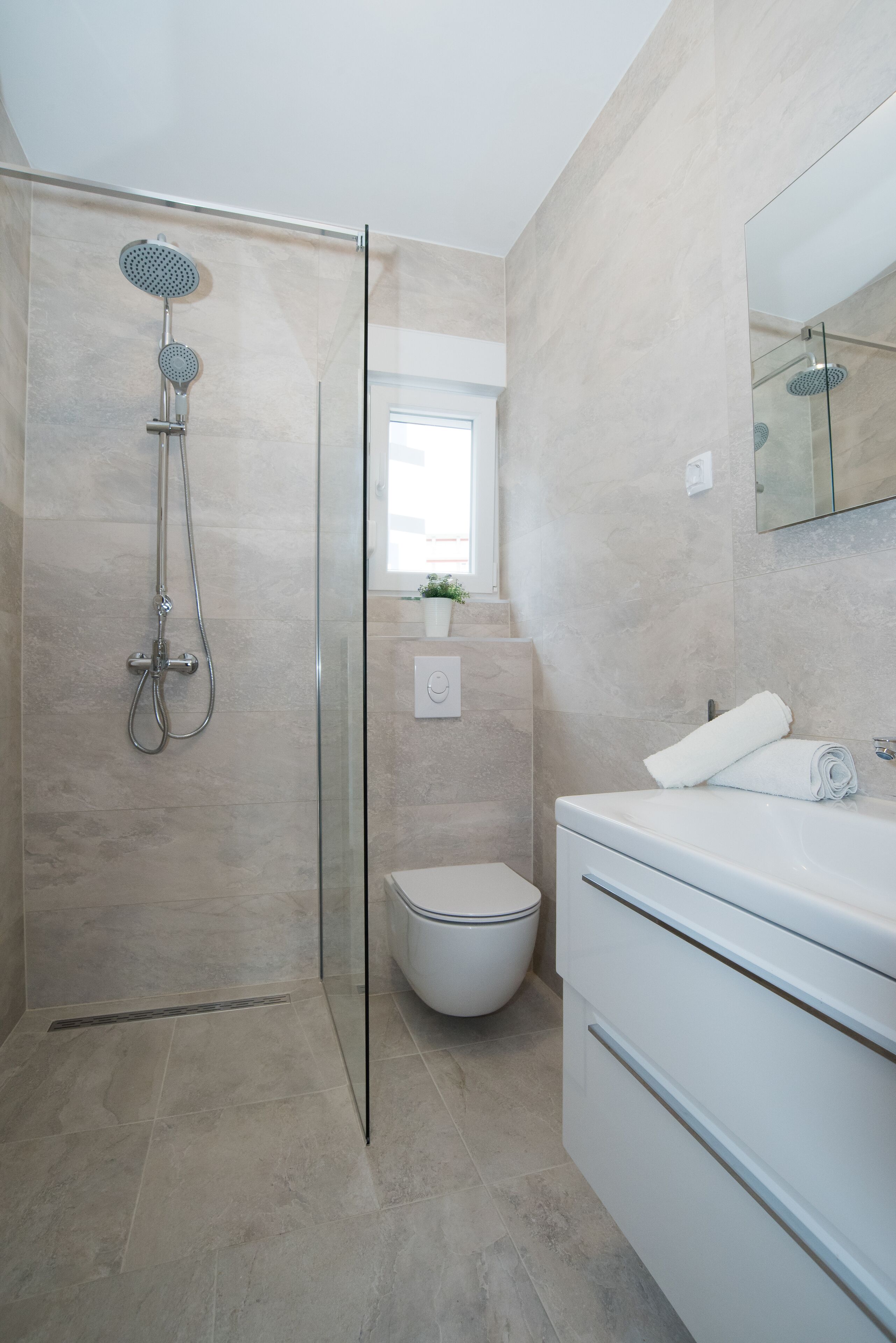 A modern bathroom with a glass-enclosed shower, a toilet, and a vanity with a mirror.