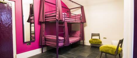 Una habitación con una litera, una silla, un espejo y una puerta.