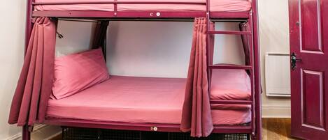 A bunk bed with pink bedding, a door to the right, and a wooden floor.