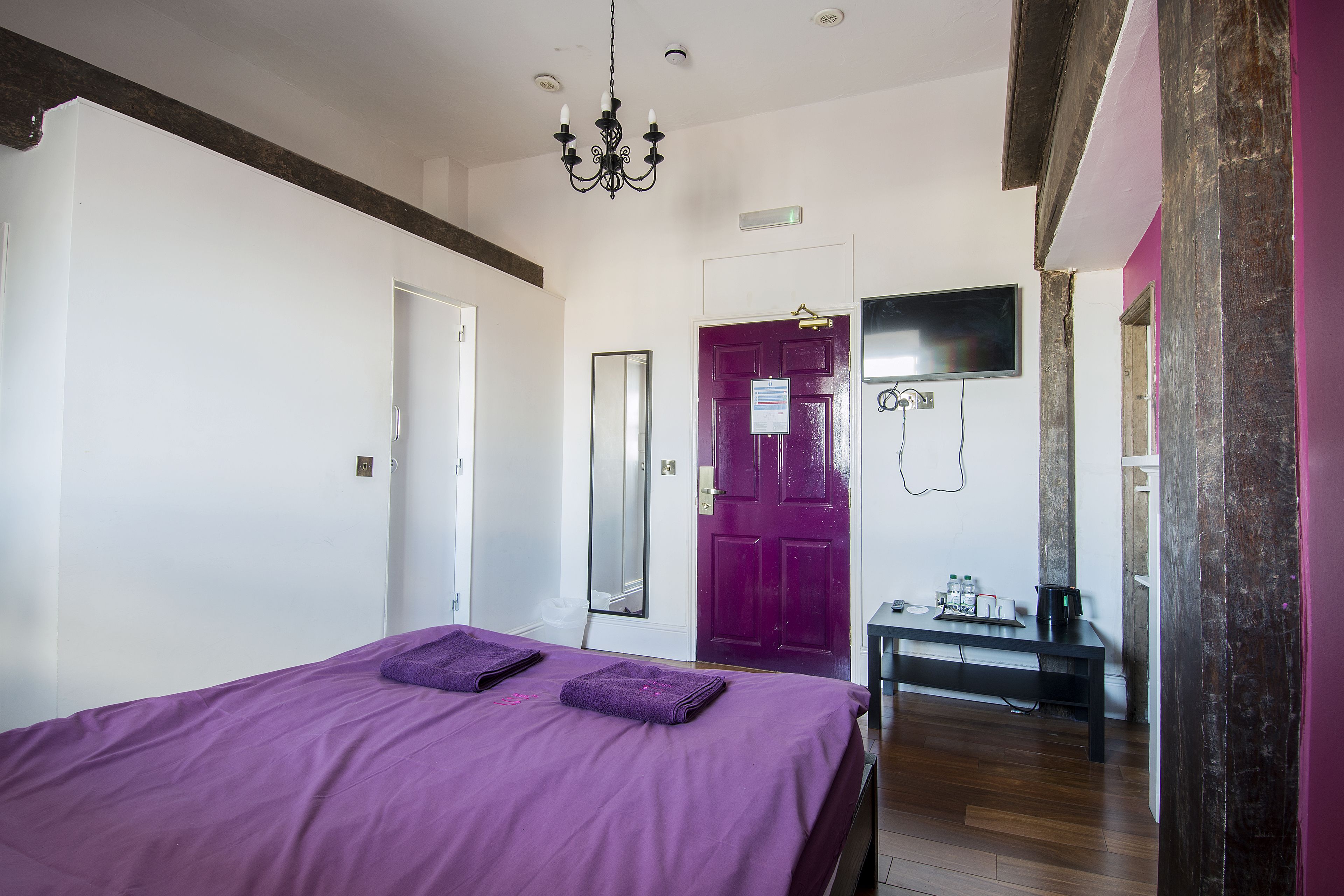 Una habitación con una cama, una mesa, un televisor y una puerta.
