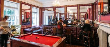 Een biljartkamer met een pooltafel, bar en zitgedeelte.