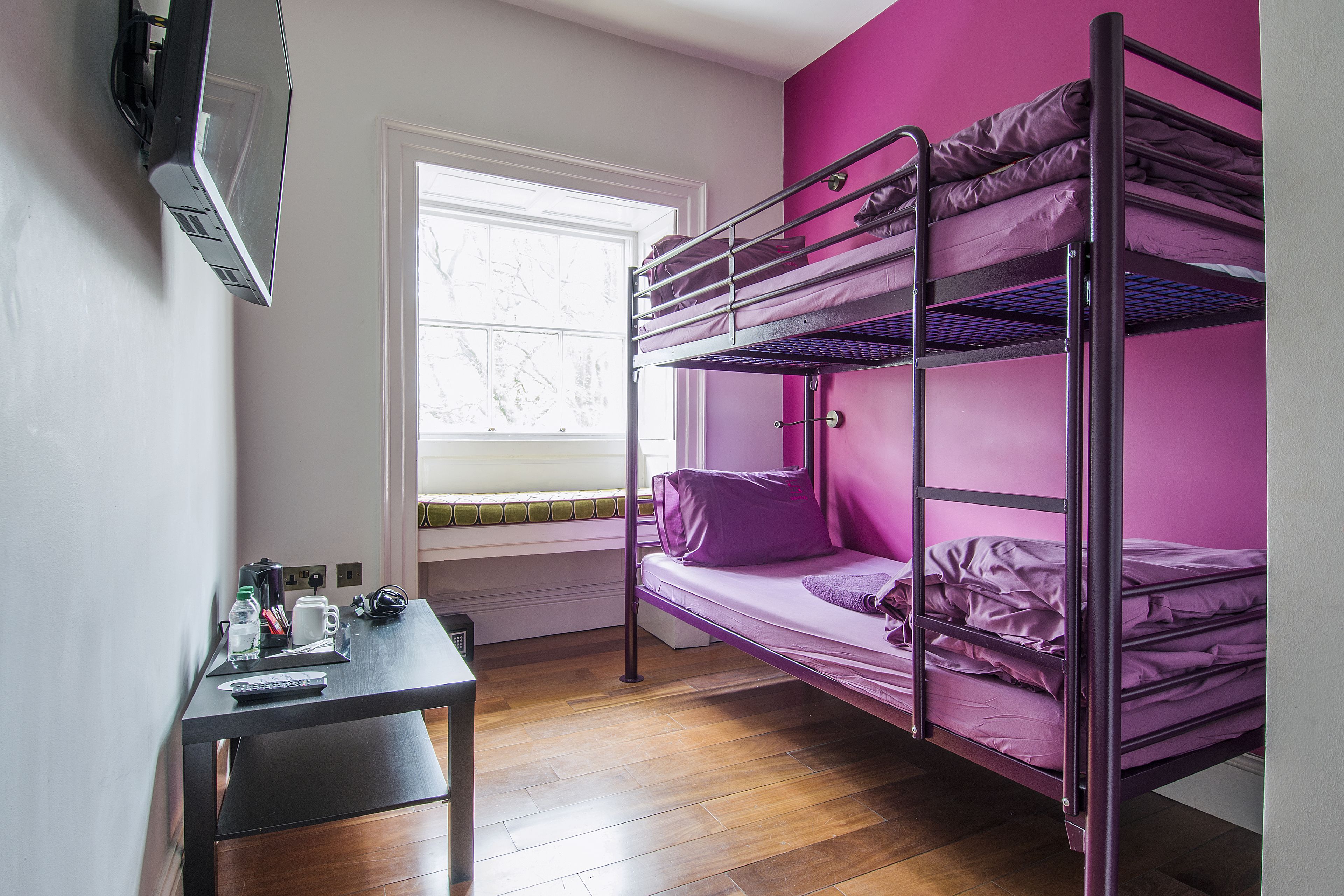 A bunk bed room with a desk and a window.