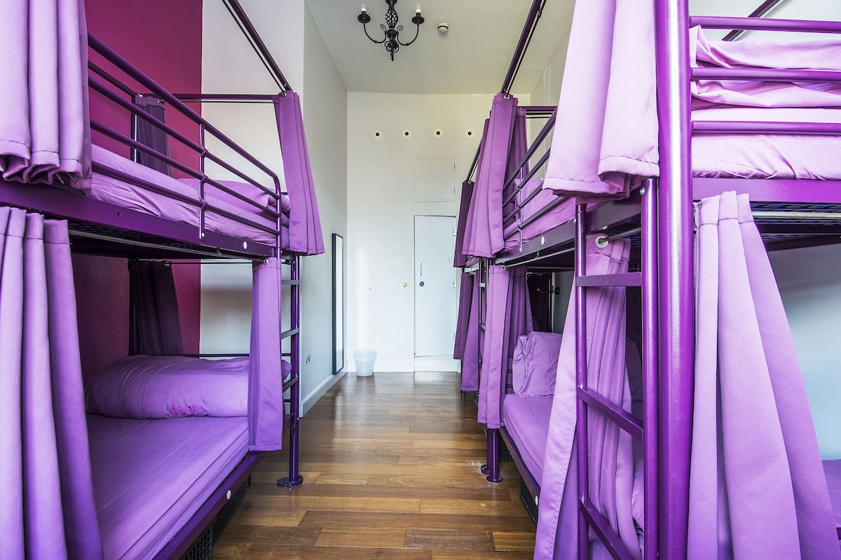 A corridor with bunk beds, wooden flooring, and a white door at the end.