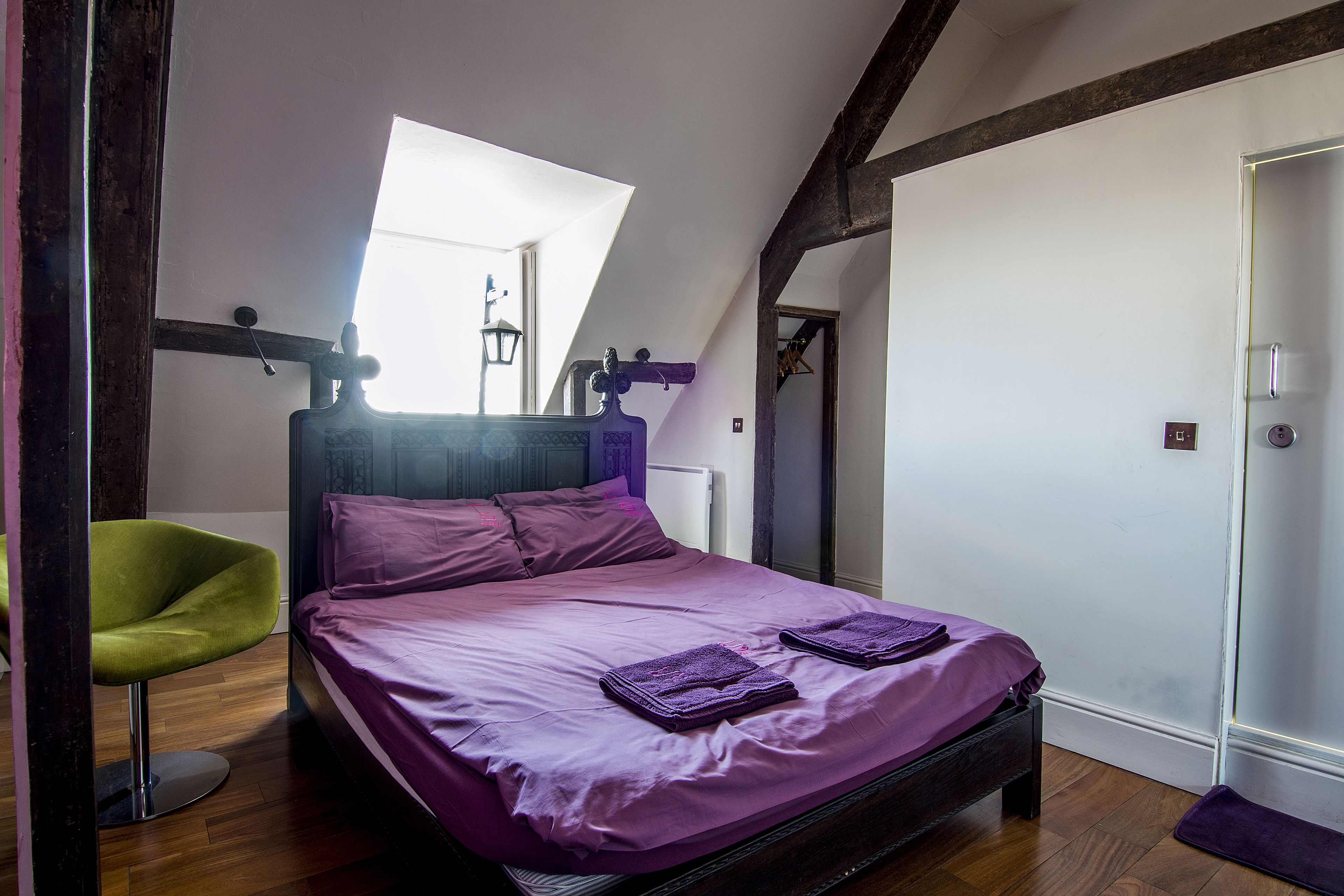 A bedroom with a bed, a chair, a window, and a door.