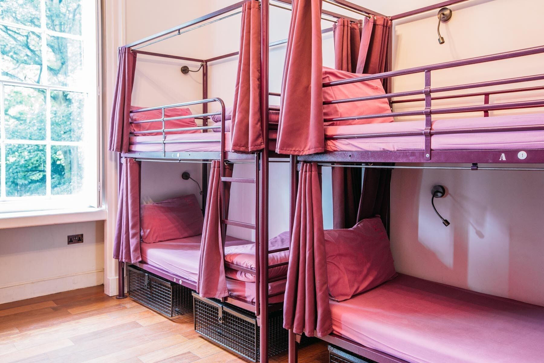 A bunk bed room with metal railings and red bedding.