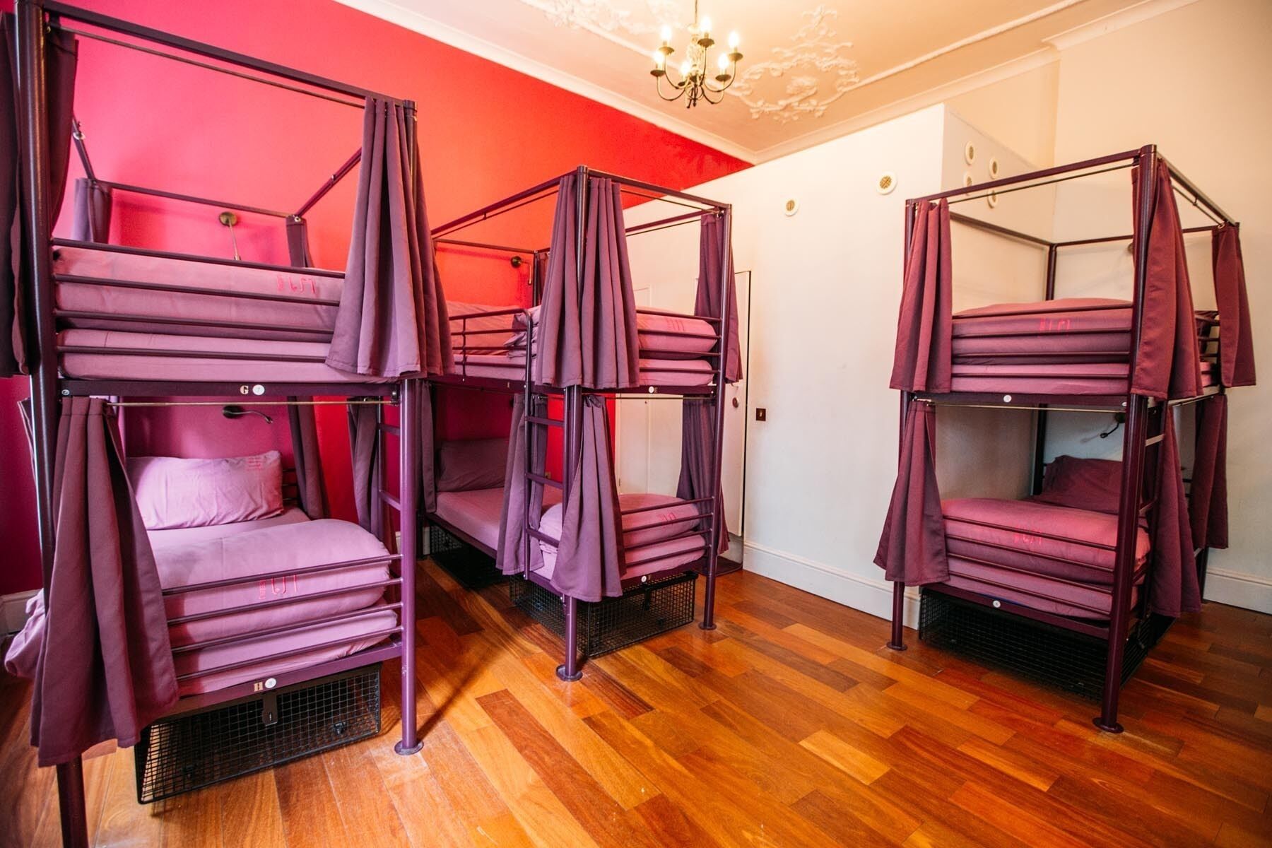Beliches com cortinas, soalho de madeira e um candelabro.