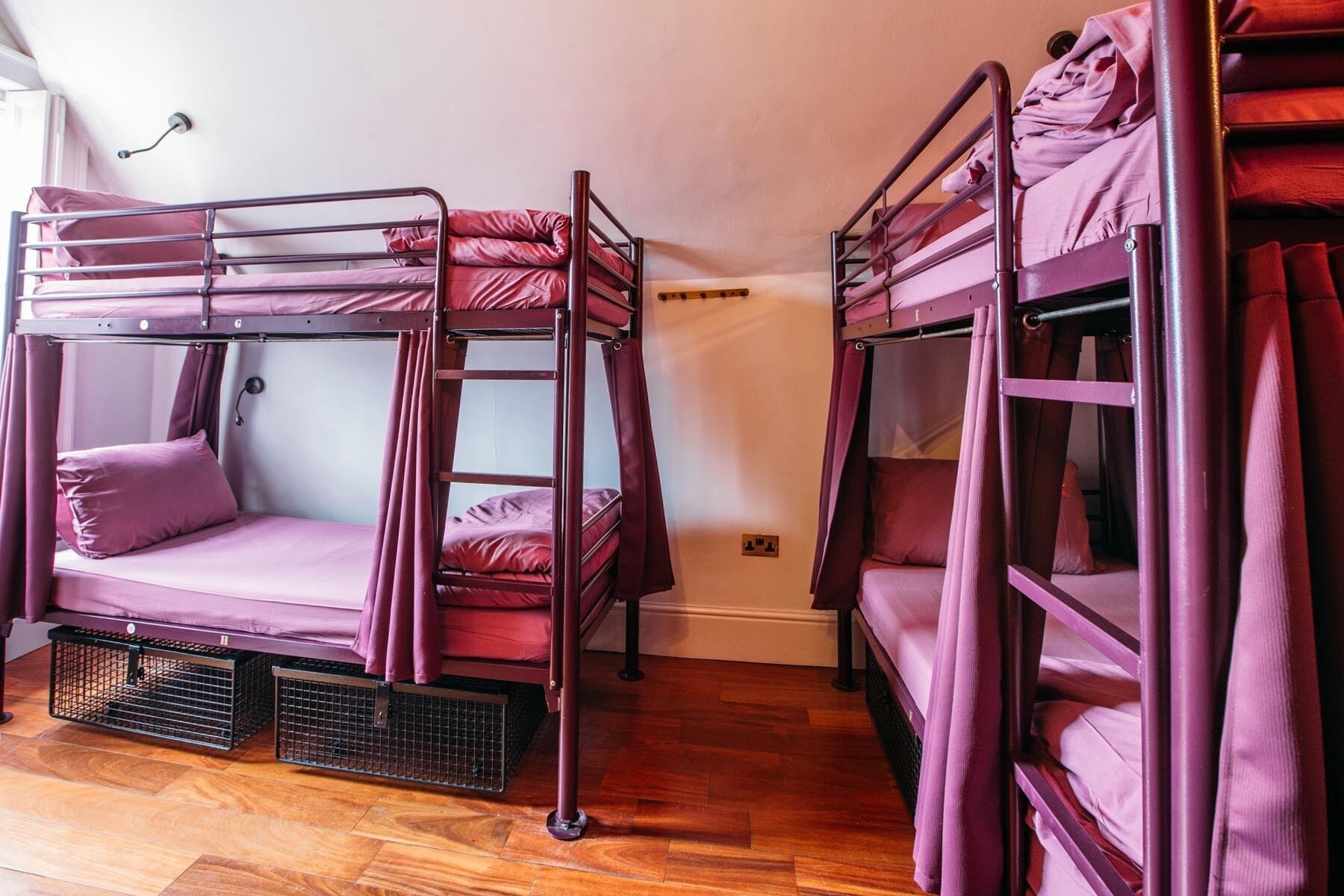 Een kamer met twee stapelbedden, elk met een matras en kussens, en een ladder om erbij te komen.