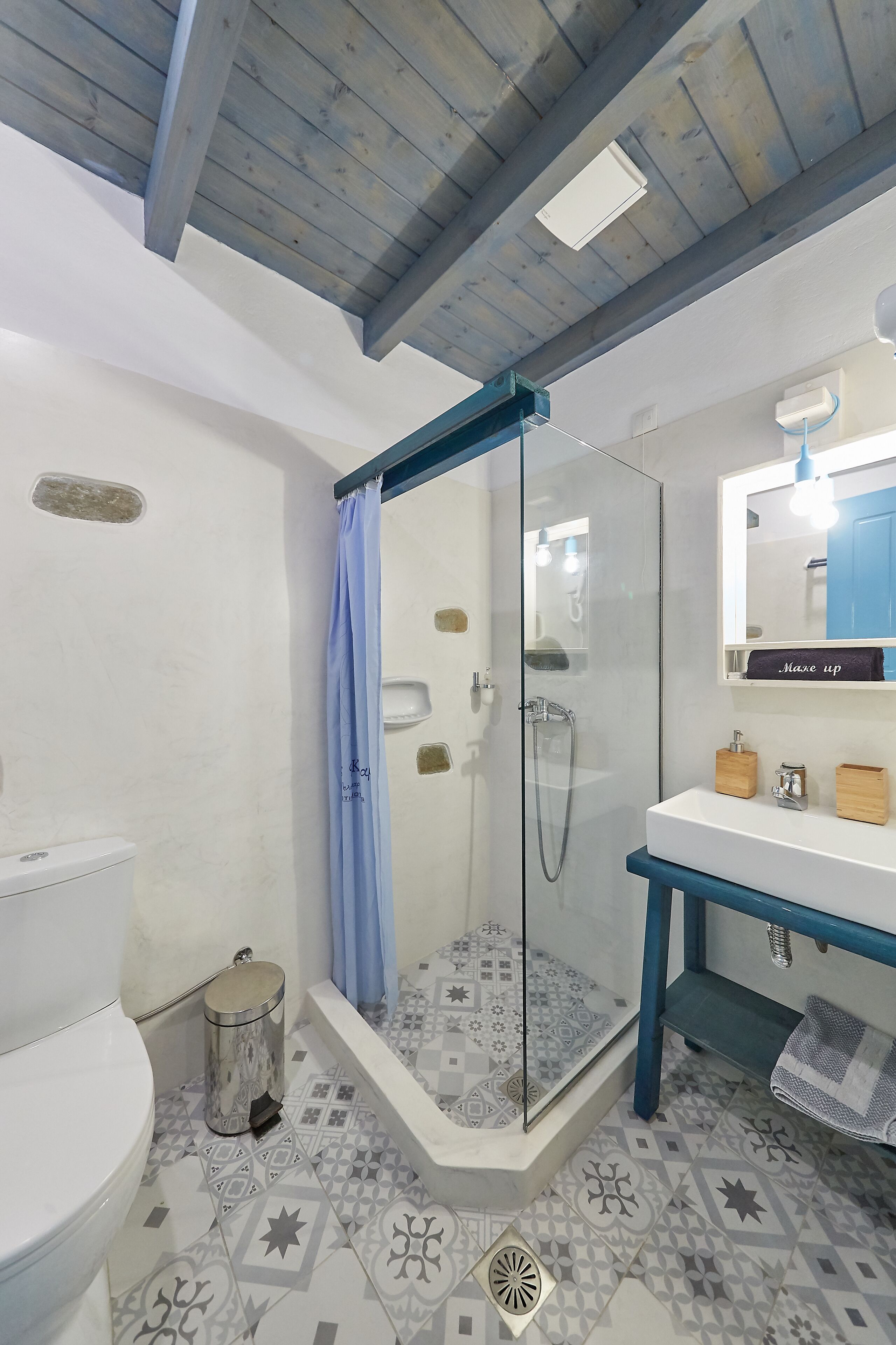 Baño con ducha, inodoro, lavabo y espejo.