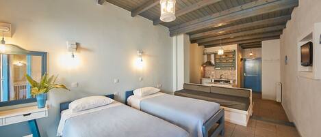 A bedroom with two beds, a desk, a mirror, and a hanging light fixture.