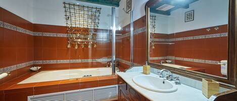 A bathroom with a large bathtub, a sink, and a mirror.