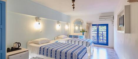 Habitación de hotel con dos camas, una kitchenette pequeña, un baño con espejo y vistas al exterior.