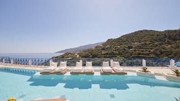Una piscina al aire libre, sombrillas, sillones reclinables de piscina
