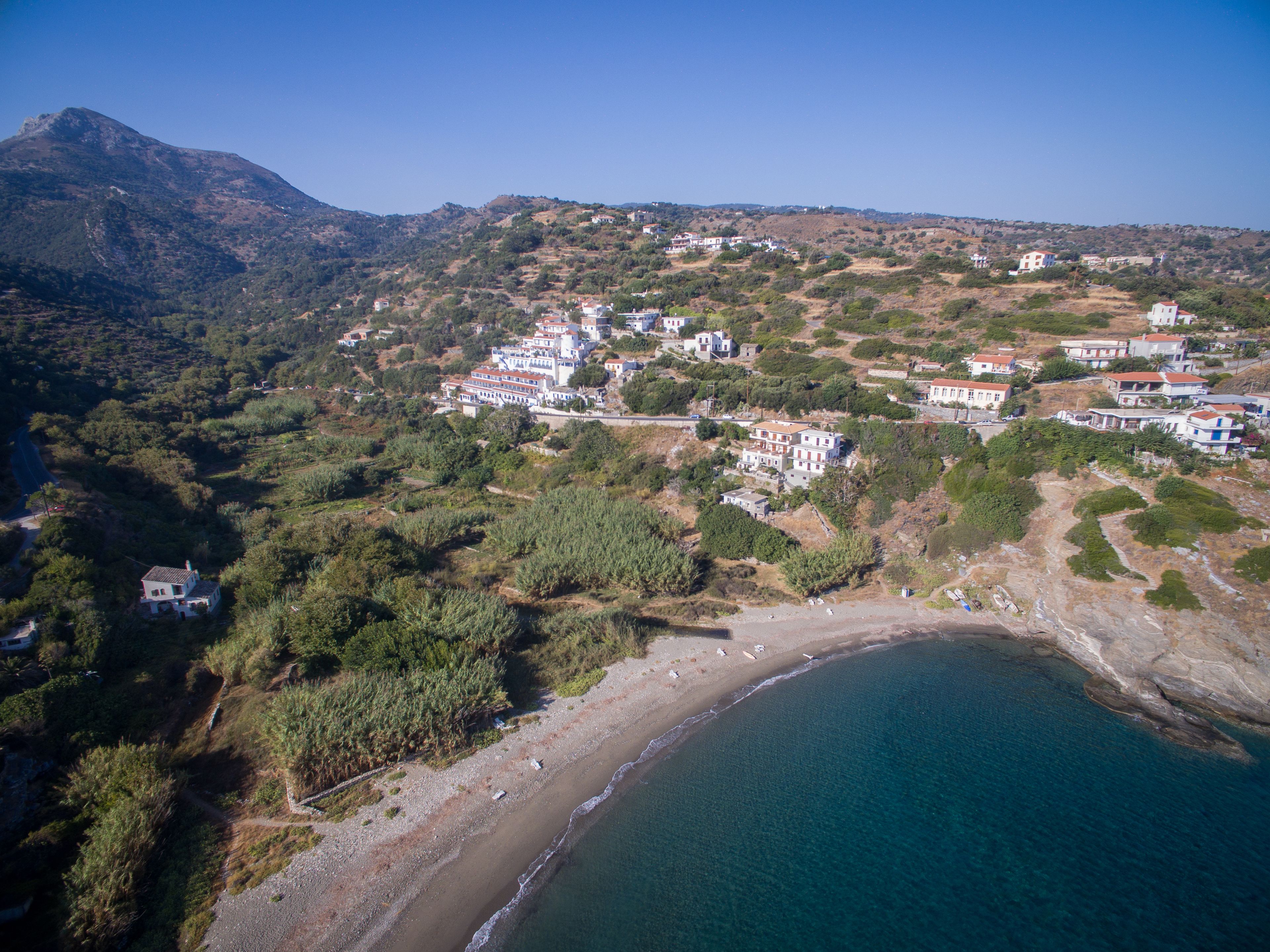 A coastal village with buildings on a hillside overlooking a beach.