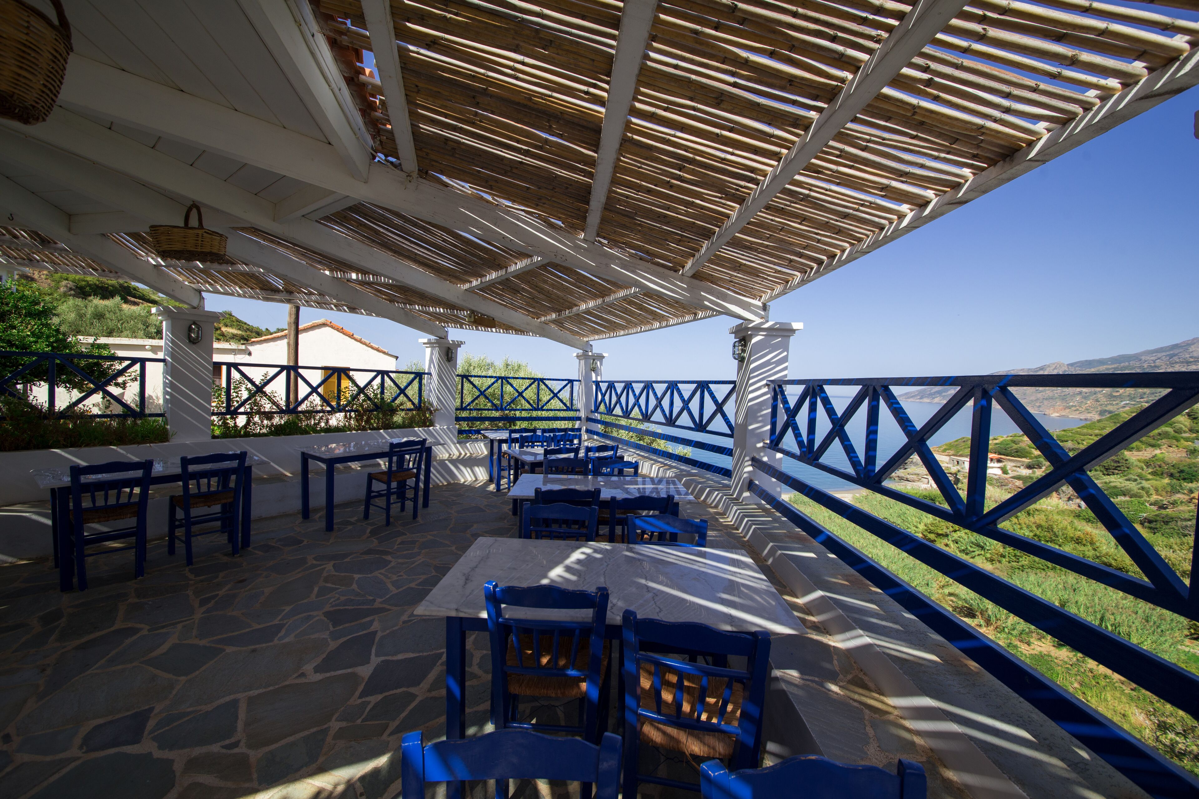 An outdoor patio with stone flooring, blue furniture, and a view of the landscape.