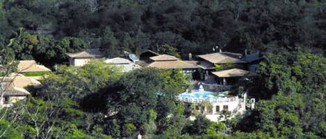 A cluster of houses surrounded by dense forest, with a visible swimming pool.