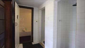 Un pasillo estrecho con un baño a la izquierda, que incluye inodoro y lavamanos.