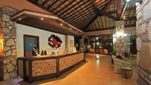 A reception area with a check-in counter, stone walls, and a high ceiling with wooden beams.