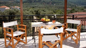 Un balcón con una mesa lista para dos personas, que incluye un frutero y una botella.