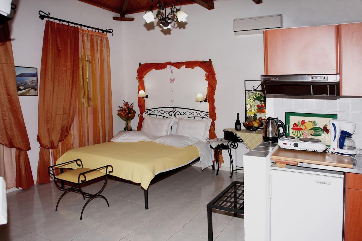 A bedroom with a bed, bedside table, and a small desk with a kettle and coffee maker.
