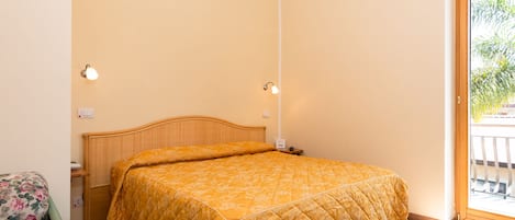 Un dormitorio con cama, mesita de noche, silla y ventana con vista a zonas verdes.
