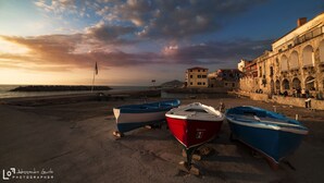 Boats on a beach with a historic building in the background.