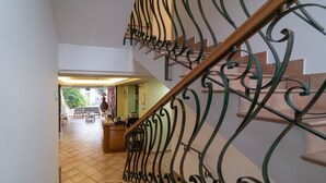 A staircase with ornate metal railings leading to a room with a tiled floor and a view of the outside.