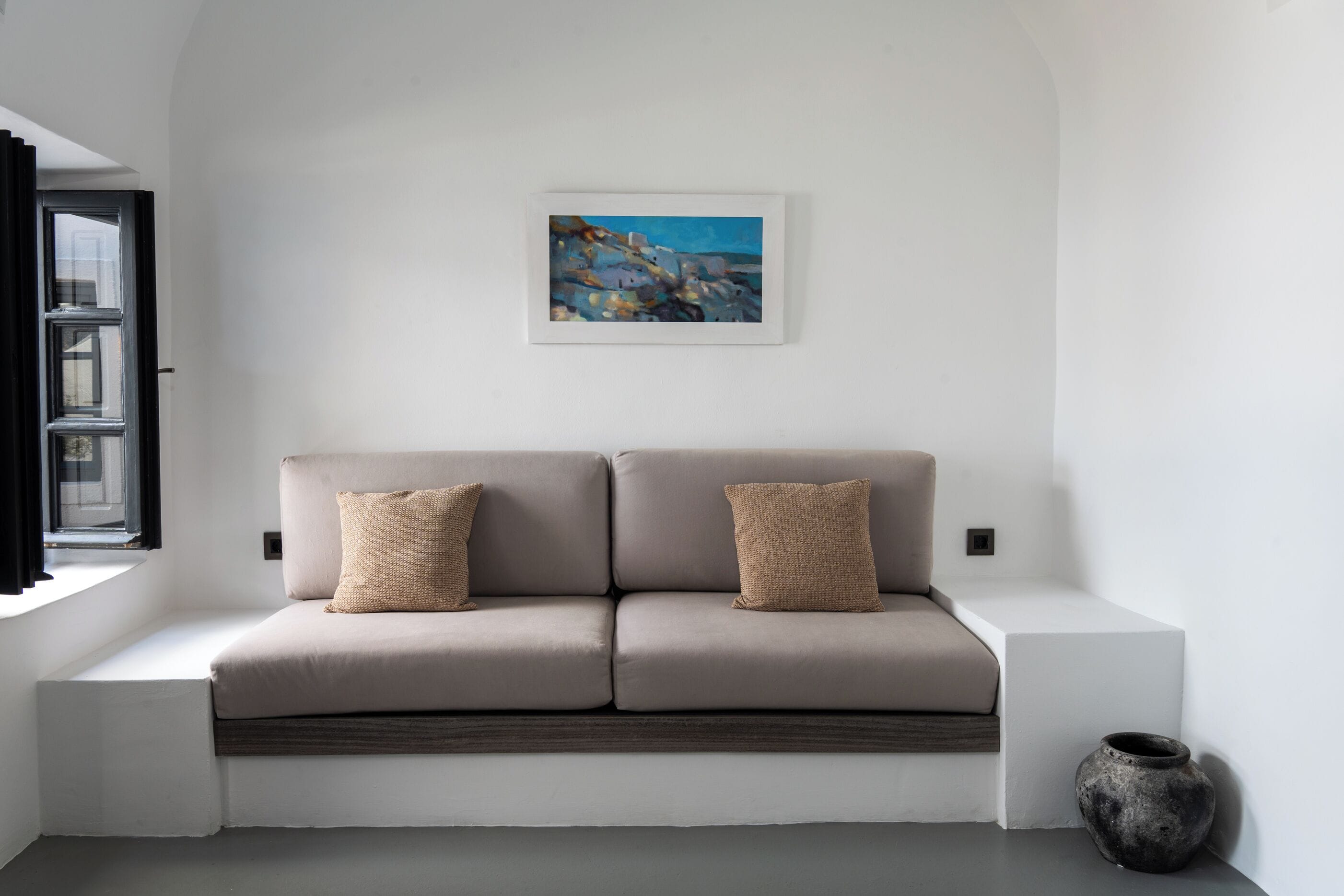 A modern living room with a sofa, a painting, and a vase.