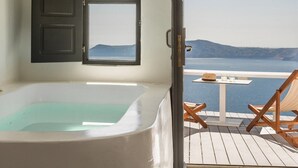 A room with a bathtub, a window, and a view of the sea. - Sun Rocks Boutique Hotel | Caldera View Suites & Sunset Dining Experience (Santorini)