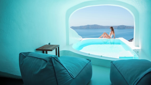 A room with a view of the sea, a bathtub, and two chairs. - Sun Rocks Boutique Hotel | Caldera View Suites & Sunset Dining Experience (Santorini)