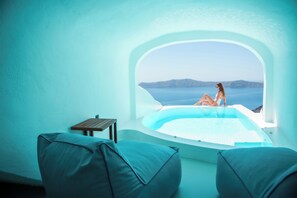 A room with a view of the sea, a bathtub, and two chairs. - Sun Rocks Boutique Hotel | Caldera View Suites & Sunset Dining Experience (Santorini)