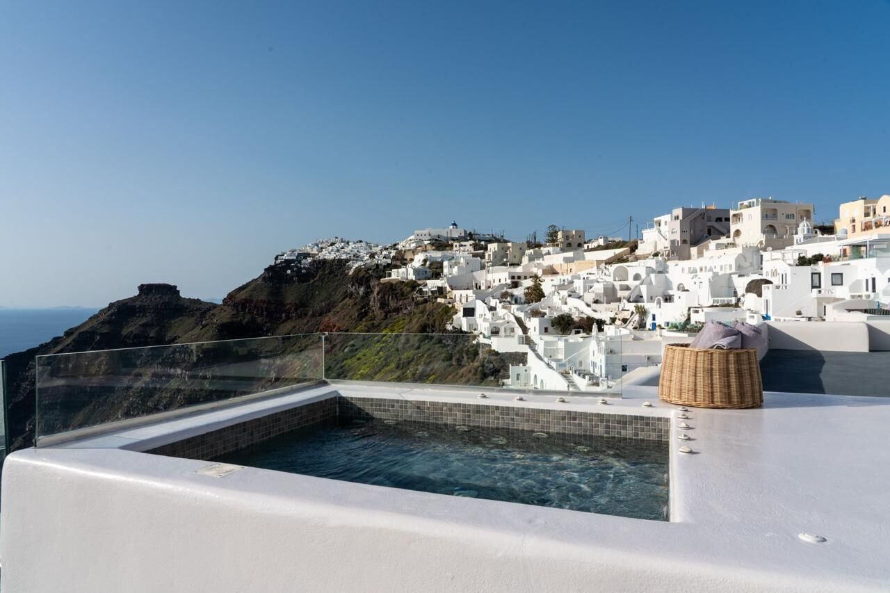 A rooftop pool with a clear view of a white-washed coastal town.