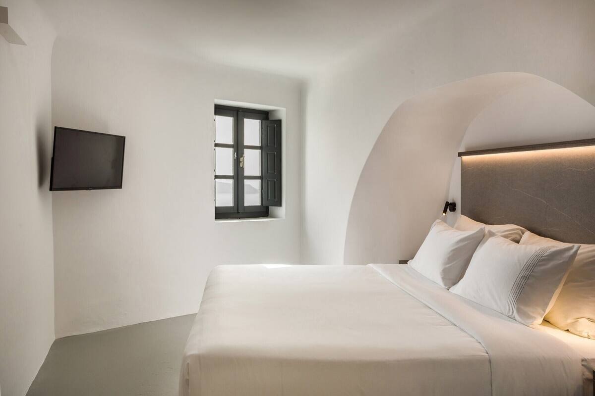 Une chambre moderne avec un lit, un téléviseur fixé au mur et une fenêtre donnant sur un beau paysage.
