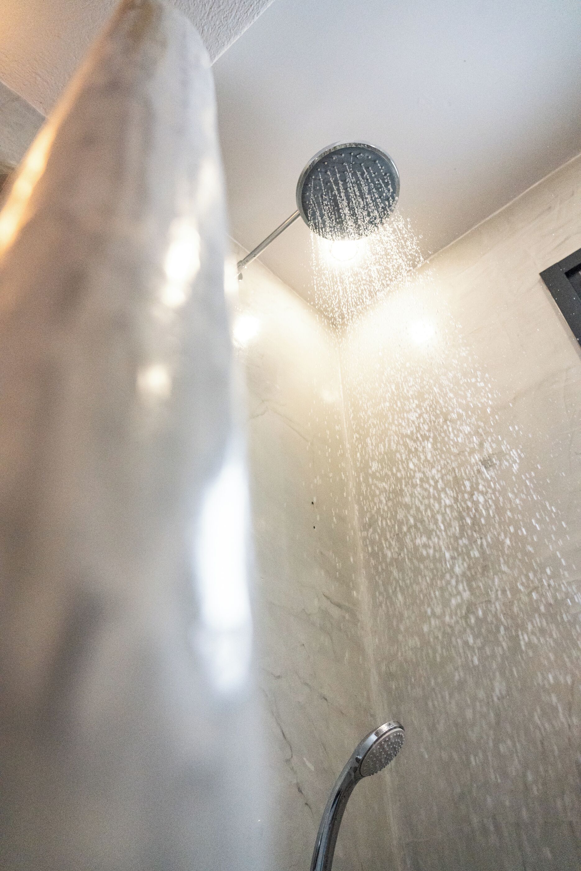 A shower with water flowing from a roundhead showerhead.