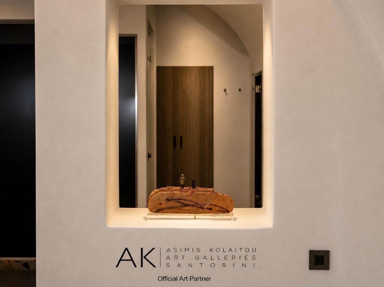 Una obra de arte enmarcada en un pasillo con una puerta de madera al fondo.
