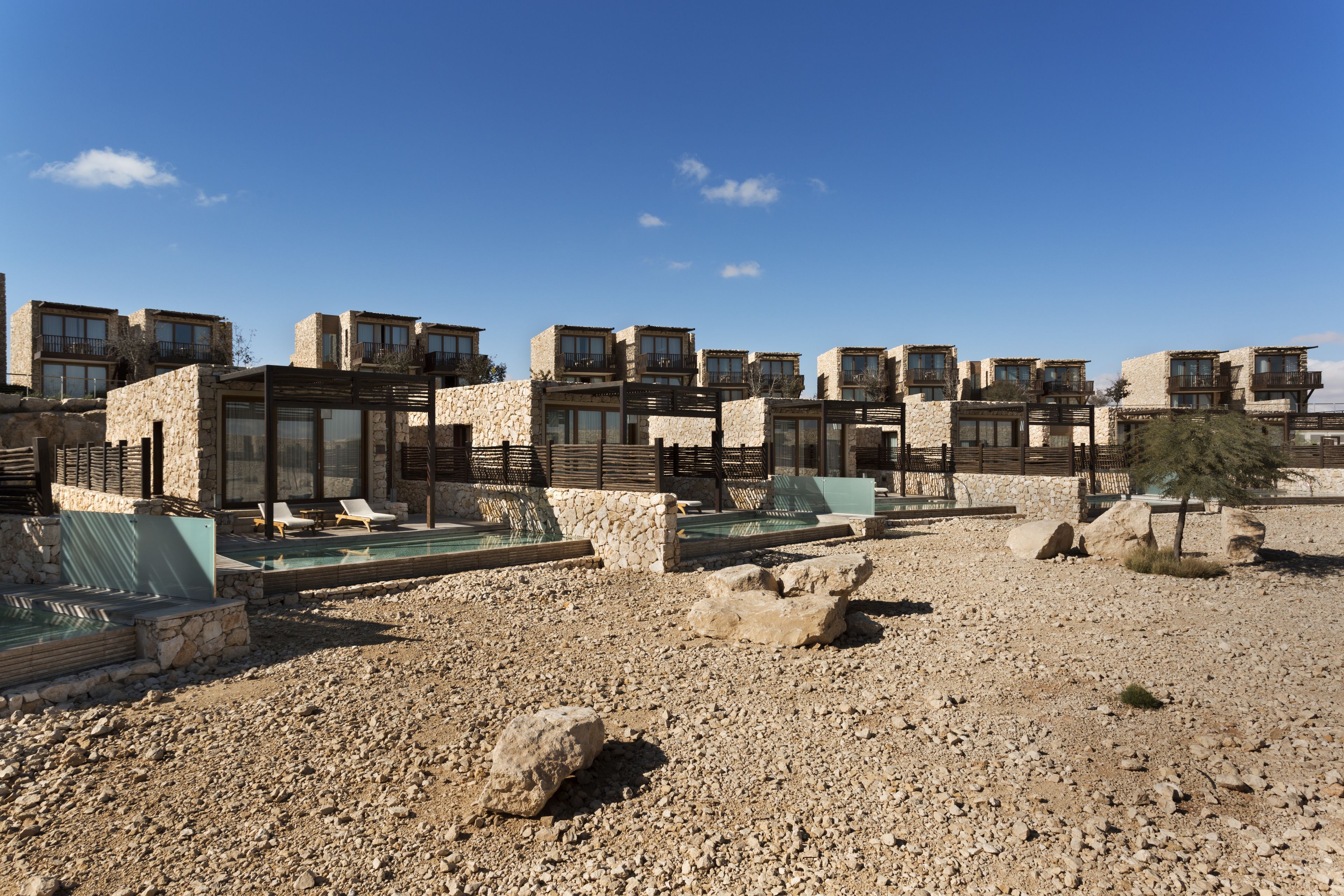 A resort with multiple stone buildings, outdoor swimming pools, and lounge chairs.
