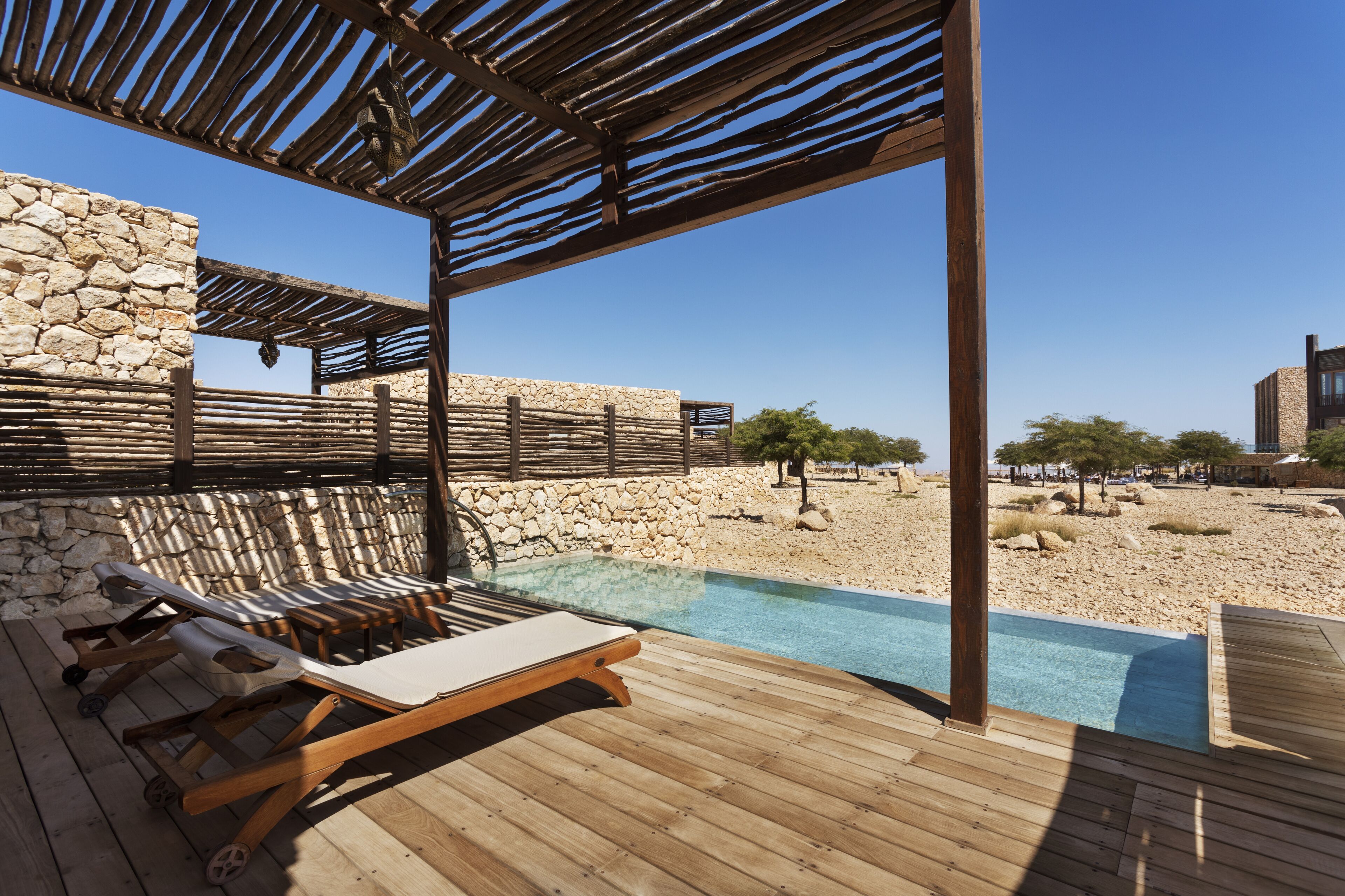 Una terraza de madera con sillas de descanso y una piscina.